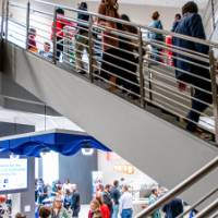 Photo of lobby area with crowd of people, people walking down stairway